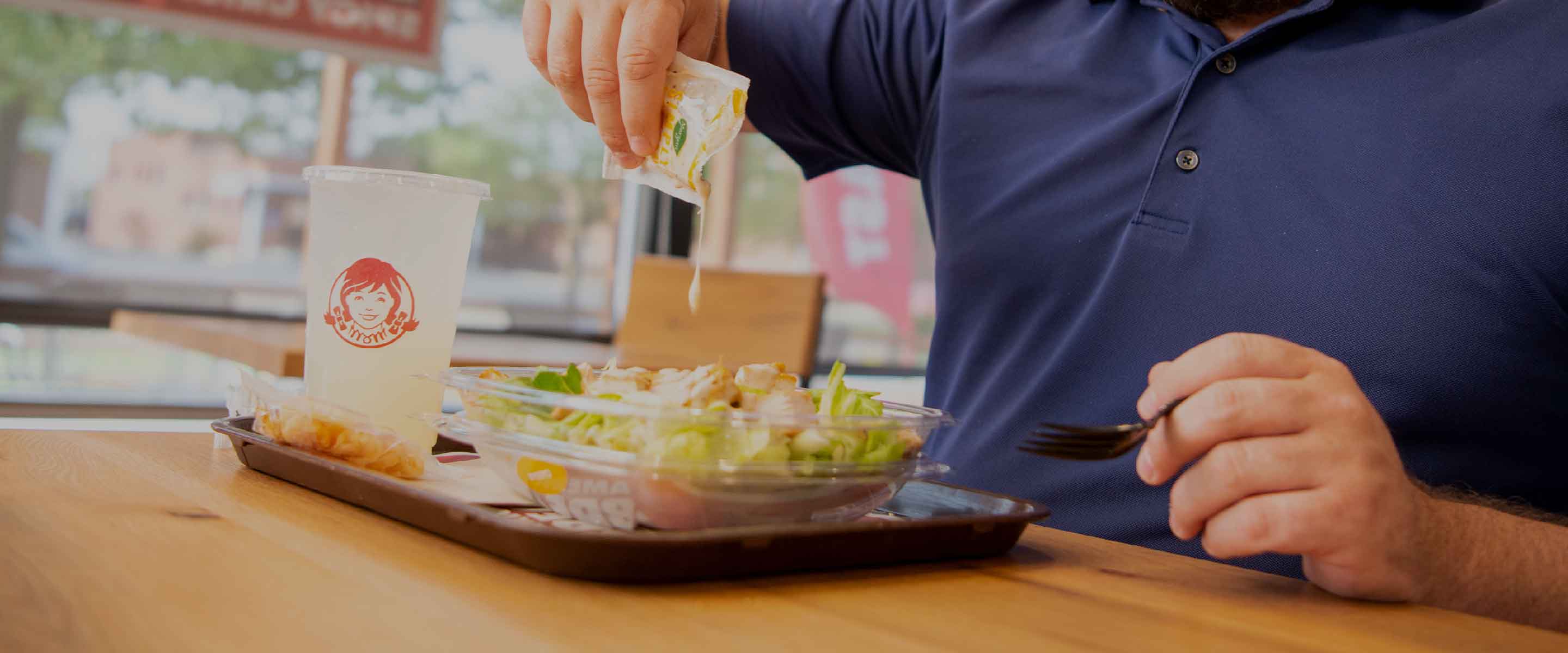 customer eating Wendy's salad and lemonade