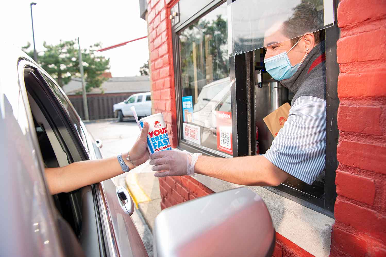 Wendy's crew member serving customer at drive-thru