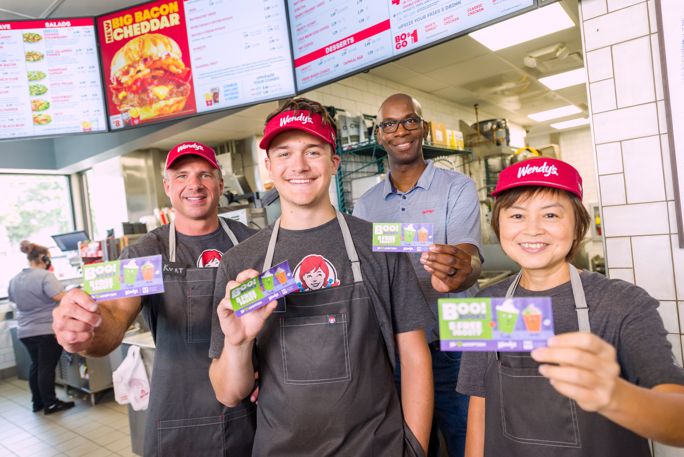 Wendy's employees holding up Halloween coupons in the store.