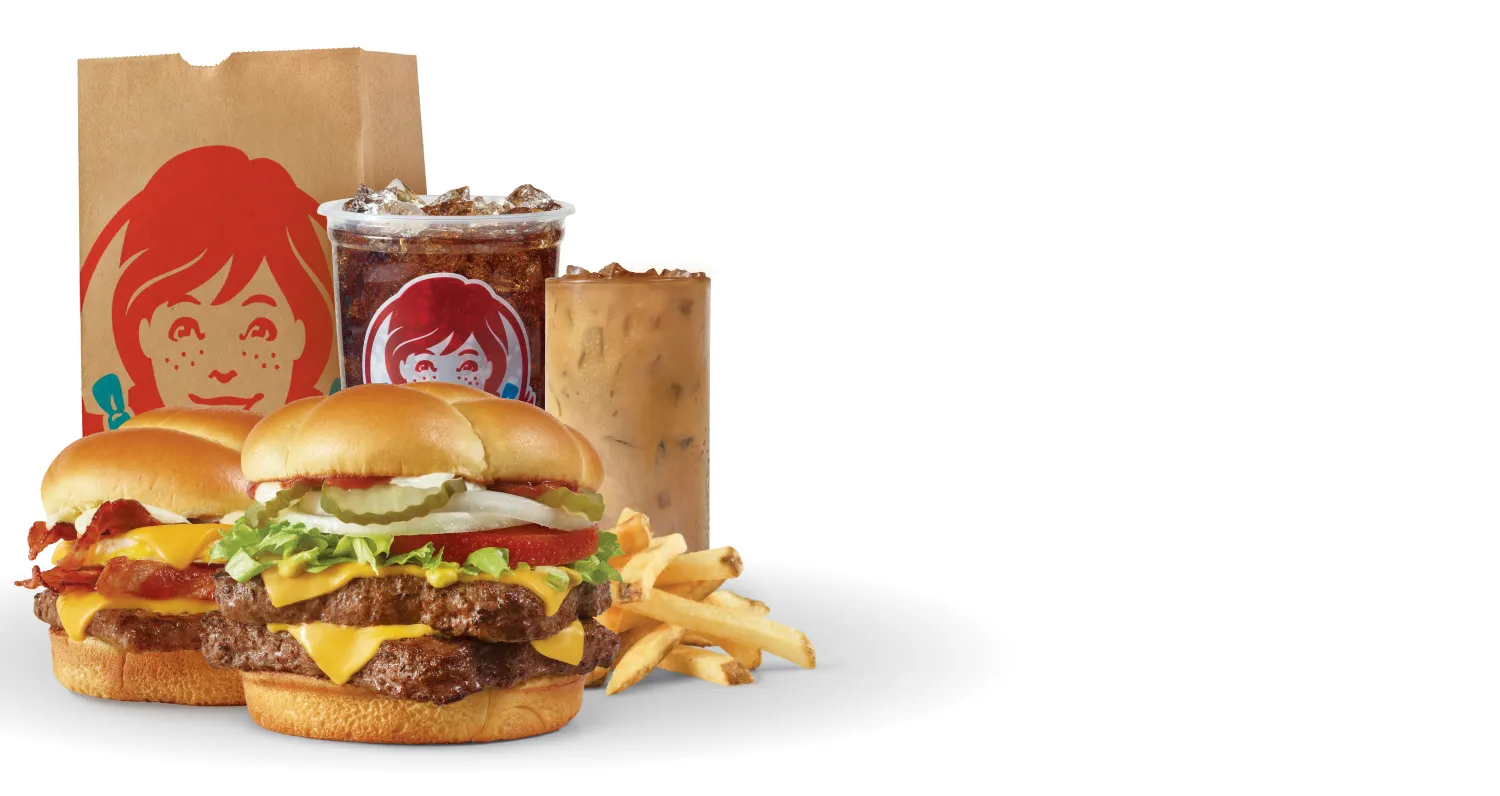 Get Wendy's Delivered: Breakfast Baconator® combo with seasoned potatoes and Frosty-ccino®, and Dave's Double® combo with fries and soft drink next to a Wendy's bag