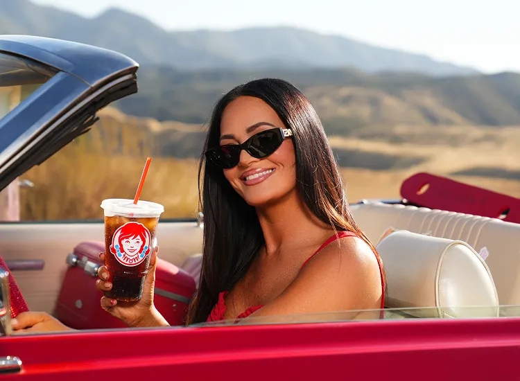 Lisa Barlow with a Wendy's cup in a red convertible