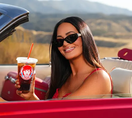 Lisa Barlow with a Wendy's cup in a red convertible